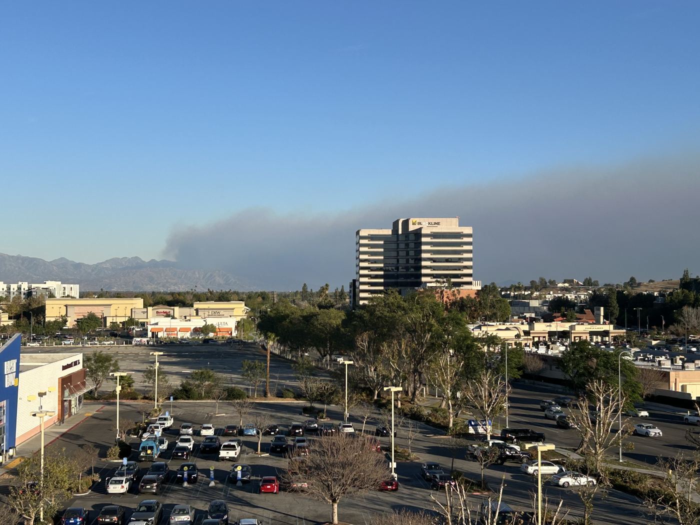 A wall of smoke from the Eaton Fire rises over the San Gabriel Mountains, seen across the basin from Woodland Hills.